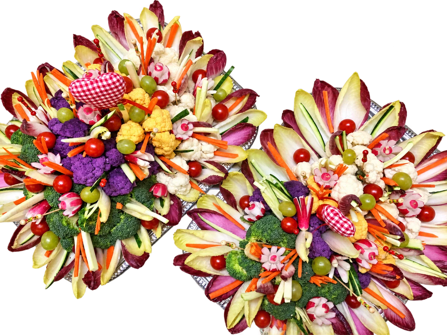 Deux plateaux de légumes crus disposés en fleurs avec endives, brocolis, chou-fleur, tomates cerises, raisins et radis sculptés sur une table en inox.